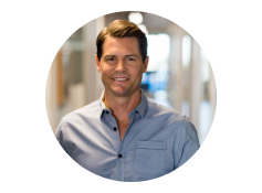 A man in a blue shirt smiling in an office.