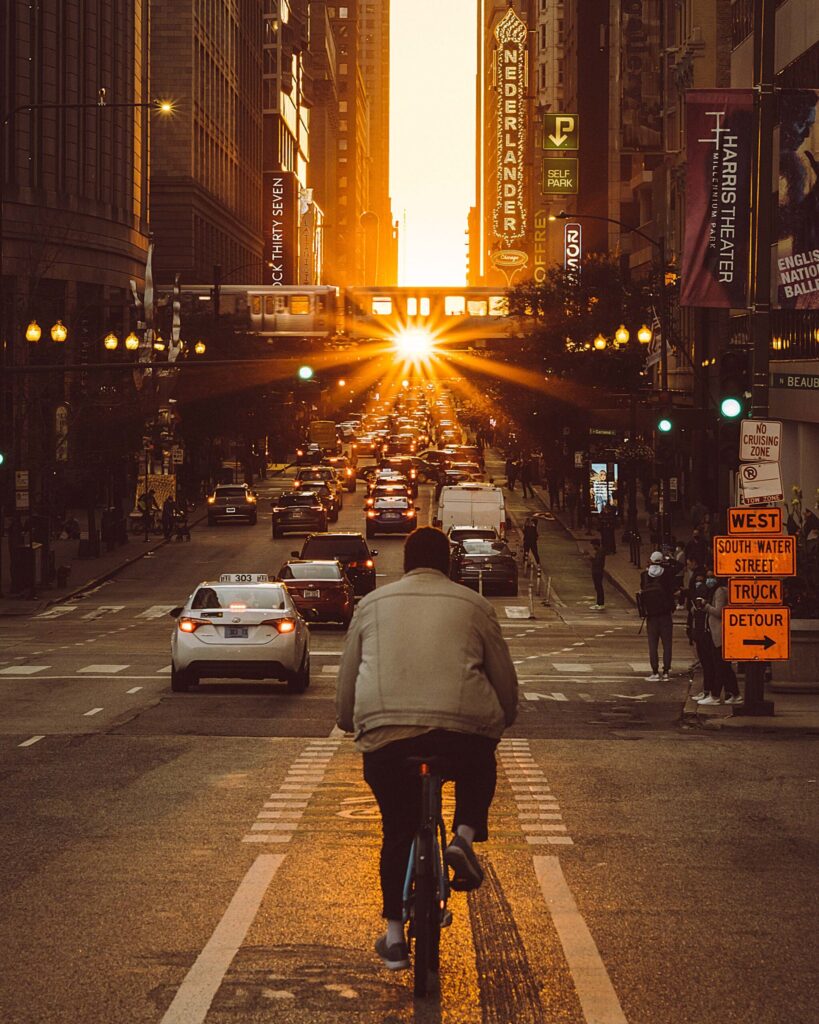 A cyclist using a well-marked bike lane, with well-placed street signs, on a Chicago road during sunset