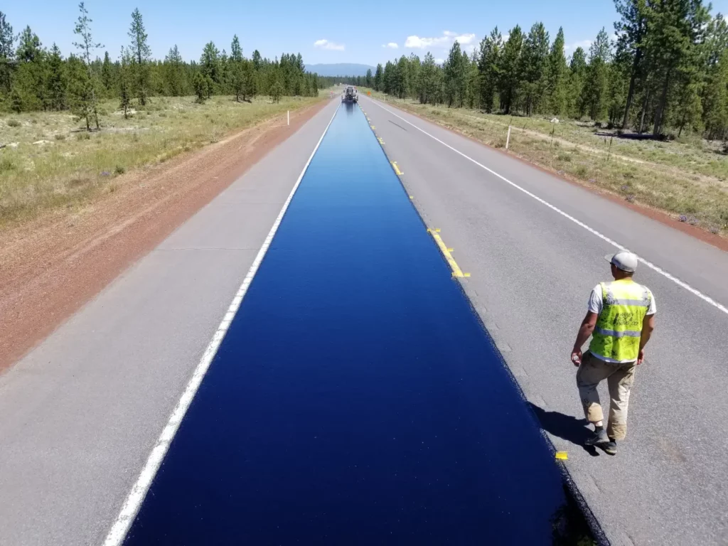 Worker walking beside freshly paved highway construction in La Pine, Oregon